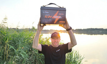 A delighted customer triumphantly holds up his new LiTime battery by a tranquil lake