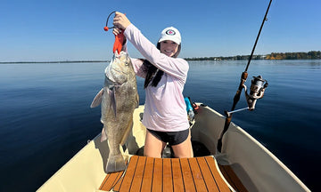 A successful fisherwoman proudly displays her catch from a boat powered by LiTime
