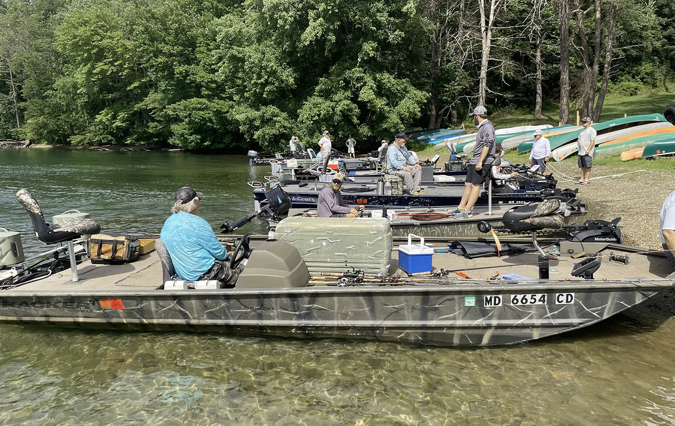 A fleet of bass boats with anglers gathered on the water near shore for the Electric Bass Anglers event