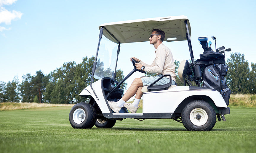 a man riding in a golf cart across a sunny golf course, demonstrating a popular use for the battery
